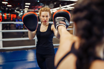 Woman in gloves boxing in the ring with trainer