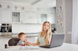© sata_production - Young mother feeding child and talking on the phone