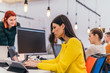 © qunica.com - Concentrated beautiful girl with long black hair and yellow blouse working on a laptop in a modern office.