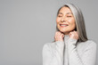© LIGHTFIELD STUDIOS - happy asian woman in turtleneck with grey hair and closed eyes isolated on grey