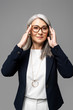 © LIGHTFIELD STUDIOS - executive asian businesswoman with grey hair in eyeglasses isolated on grey