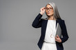 © LIGHTFIELD STUDIOS - attractive confident asian businesswoman with grey hair holding laptop isolated on grey