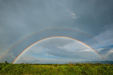  beautiful double rainbow on clouds  rainy day in rice field. after rain concept fresh air