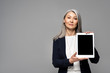 © LIGHTFIELD STUDIOS - attractive asian businesswoman presenting digital tablet with blank screen isolated on grey