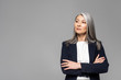 © LIGHTFIELD STUDIOS - confident asian stylish businesswoman with grey hair and crossed arms isolated on grey