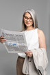© LIGHTFIELD STUDIOS - smiling asian businesswoman in eyeglasses reading business newspaper isolated on grey