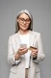 © LIGHTFIELD STUDIOS - attractive asian businesswoman with grey hair shopping online with credit card and smartphone isolated on grey