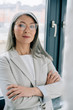 © LIGHTFIELD STUDIOS - confident asian businesswoman with crossed arms in grey suit and eyeglasses in office
