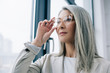 © LIGHTFIELD STUDIOS - thoughtful asian businesswoman with grey hair in grey suit and eyeglasses in office