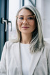 © LIGHTFIELD STUDIOS - attractive asian businesswoman with grey hair in grey suit and eyeglasses in office