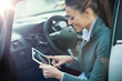 © StockPhotoPro - Smiling woman in a car with tablet
