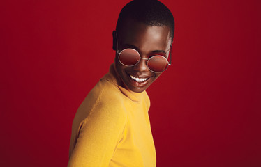 Wall Mural - Fashionable woman in sunglasses on red background