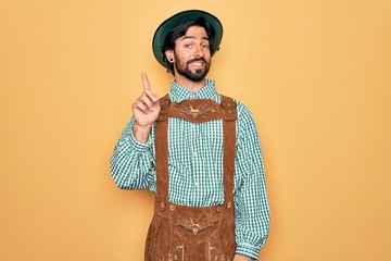 Wall Mural - Young handsome man wearing tratidional german octoberfest custome for Germany festival pointing finger up with successful idea. Exited and happy. Number one.