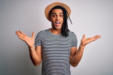 Wall Mural - Young african american man with dreadlocks on vacation wearing striped t-shirt and hat celebrating crazy and amazed for success with arms raised and open eyes screaming excited. Winner concept