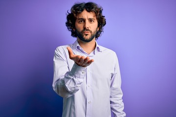 Young handsome business man with beard wearing shirt standing over purple background looking at the camera blowing a kiss with hand on air being lovely and sexy. Love expression.