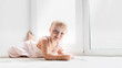© natalialeb - Caucasian baby girl lies and paints on windowsill