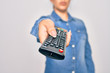 © Krakenimages.com - Woman changing television channel holding tv remote control. Standing over isolated white background