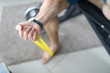 Close-up of person exercising with yellow fitness rubber band. Man training arm at home. Macro shot of man getting stronger. Sport and fit body on quarantine concept