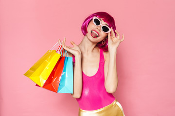 Wall Mural - Image of amusing girl sticking out her tongue and holding shopping bags