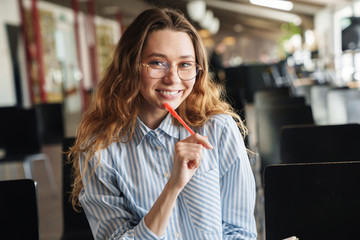 Sticker - Image of cheerful woman smiling and writing on planner while sitting