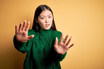 Sticker - Young beautiful asian woman wearing green winter sweater over yellow isolated background doing stop gesture with hands palms, angry and frustration expression