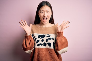 Wall Mural - Young beautiful asian woman wearing animal print fashion sweater over pink isolated background celebrating crazy and amazed for success with arms raised and open eyes screaming excited. Winner concept