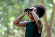 Little African American Girl with Binoculars during Hiking in Forest.