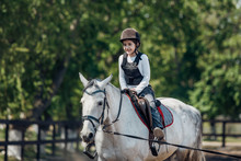 Little Girl In Helmet Learning Horseback Riding. Instructor Teaches Kid Equestrian.