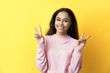 © GVS - Happy smiling black woman doing victory sign on yellow background.