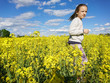 little girl. Endless fields of rapeseed blooming under a blue sky with clouds