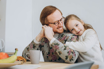 Little girl wishes dad happy father's day. Daughter hugs dad.