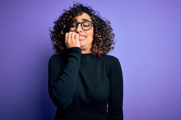 Sticker - Young beautiful curly arab woman wearing casual sweater and glasses over purple background looking stressed and nervous with hands on mouth biting nails. Anxiety problem.