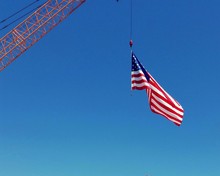 Low Angle View Of American Flag Hanging On Crane Against Clear Blue Sky