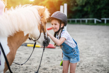 Cute Little Girl Enjoying With Pony Horse Outdoors At Ranch.