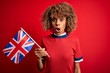 © Krakenimages.com - Young african american curly woman holding uk flag celebrating brexit referendum scared in shock with a surprise face, afraid and excited with fear expression