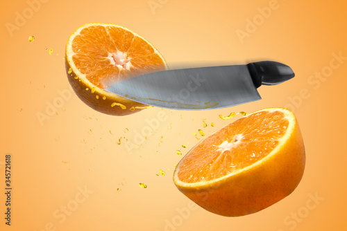 Fotomural Naranja que esta rebanada a la mitad por un cuchillo, salpicando gotas de jugo