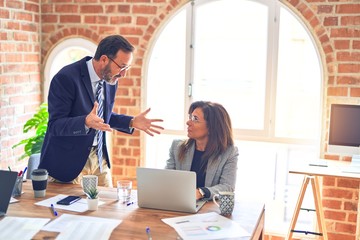 Two middle age business workers working together. Man bullying woman at the office