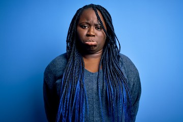 Poster - African american plus size woman with braids wearing casual sweater over blue background depressed and worry for distress, crying angry and afraid. Sad expression.