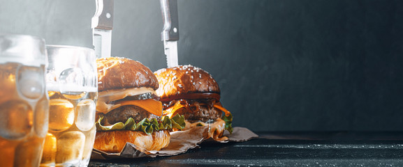 Wall Mural - two delicious beef burger on a wooden table near two glass of cold beer