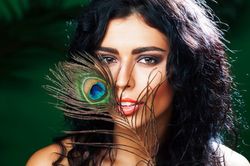 young sensitive brunette woman with peacock feather eyes closeup on green smiling, lifestyle people concept macro