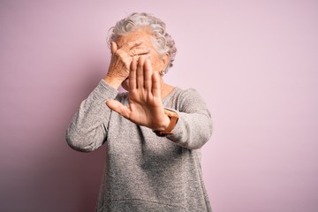 Wall Mural - Senior beautiful woman wearing casual t-shirt standing over isolated pink background covering eyes with hands and doing stop gesture with sad and fear expression. Embarrassed and negative concept.