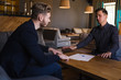 © Nickolay - Businessmen congratulated themselves on their foresight in keeping out of it in cafe.