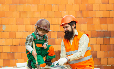 Wall Mural - Family repairs during covid quarantine pandemic. Construction. Building a new house. Quality housing. Construction worker checking location site with wall on the background. Man and boy work.