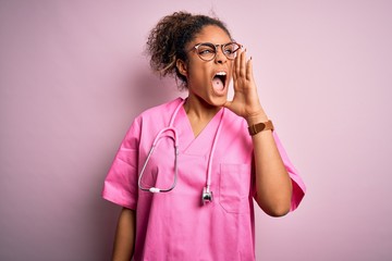 Sticker - African american nurse girl wearing medical uniform and stethoscope over pink background shouting and screaming loud to side with hand on mouth. Communication concept.