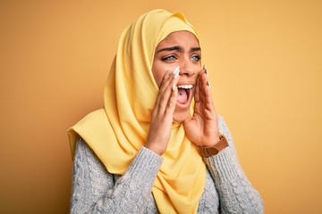 Sticker - Young beautiful african american girl wearing muslim hijab over isolated yellow background Shouting angry out loud with hands over mouth