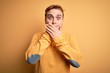 © Krakenimages.com - Young handsome redhead man wearing casual sweater over isolated yellow background shocked covering mouth with hands for mistake. Secret concept.