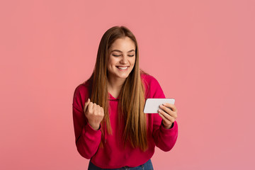 Wall Mural - Victory concept. Happy girl looks at smartphone