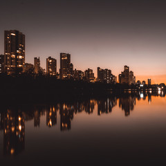 night in the city reflected in the lake with orange sunset