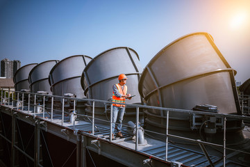 A engineer under checking the industry cooling tower air conditioner is water cooling tower air chiller HVAC of large industrial building to control air system.