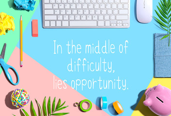 In the middle of difficulty lies opportunity message with office supplies and a computer keyboard